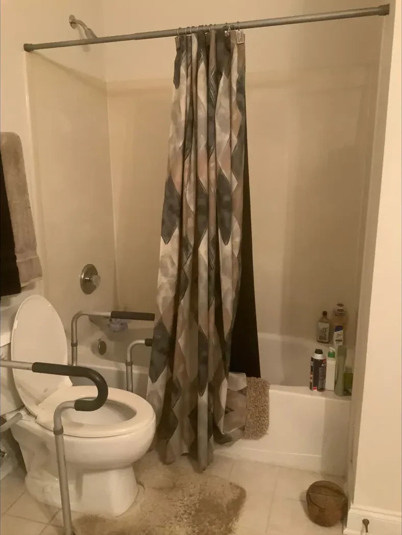 Standard tub with a shower curtain and grab bar before remodeling