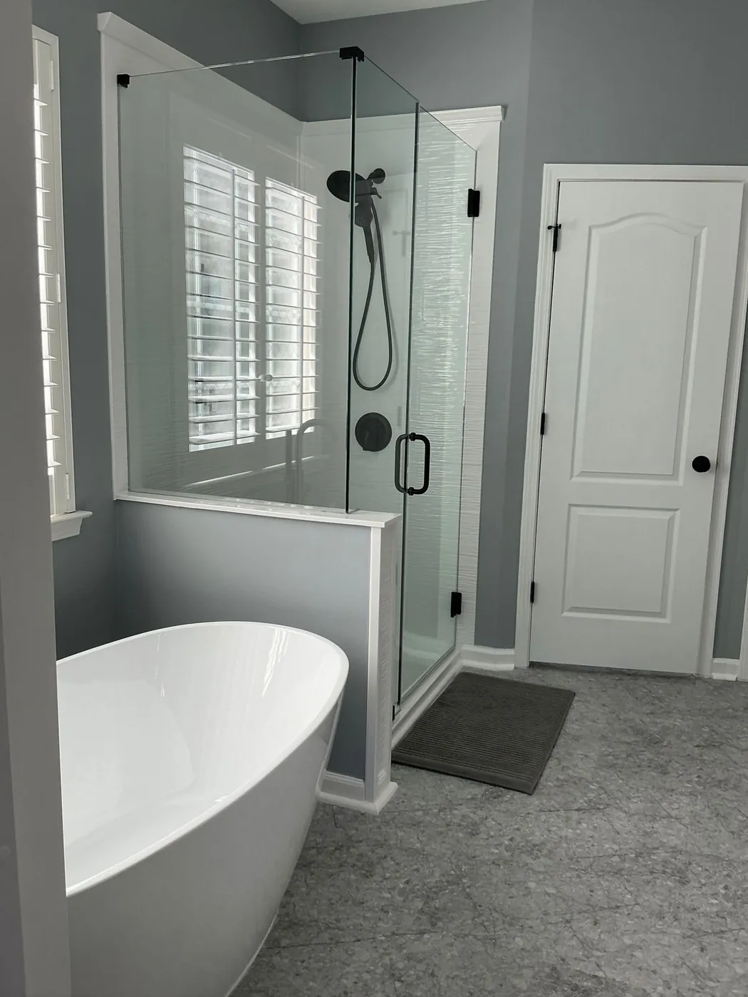 Freestanding tub beside a new glass shower after remodeling