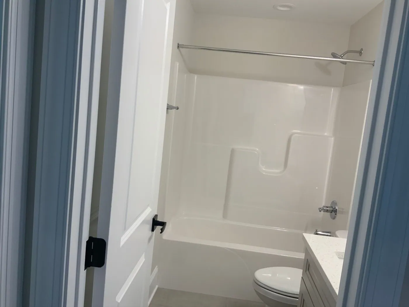 Acrylic tub and shower unit in a guest bathroom before remodeling