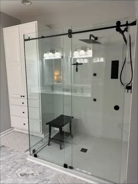Walk-in shower with a corner seat and sliding glass door after remodeling