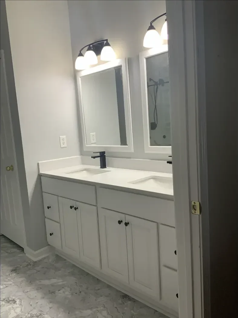 White double vanity with framed mirrors and new flooring after remodeling