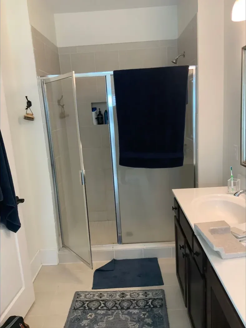 Framed metal shower enclosure and dated finishes before remodeling