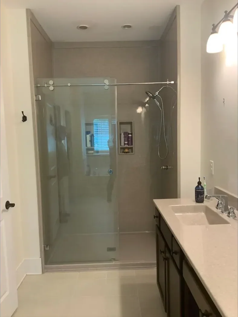 Glass shower enclosure with light stone walls after remodeling