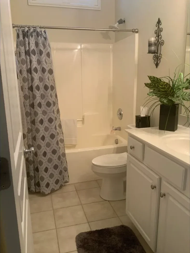 Hall bathroom with a curtained tub and shower before remodeling