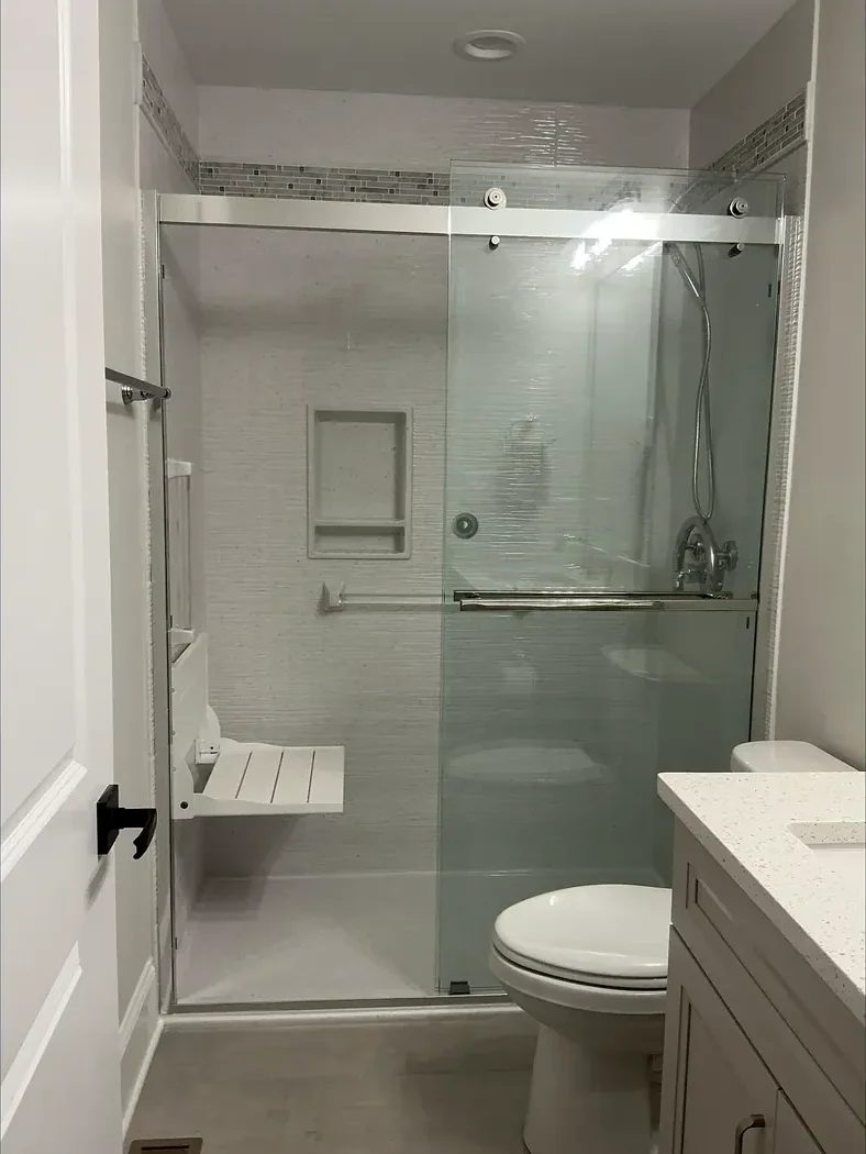 Walk-in shower with a built-in bench and glass panel after remodeling