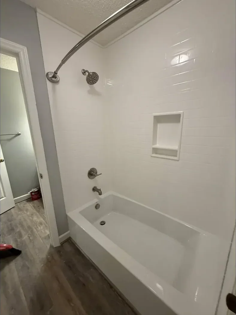 New white tub and shower surround with a recessed niche after remodeling